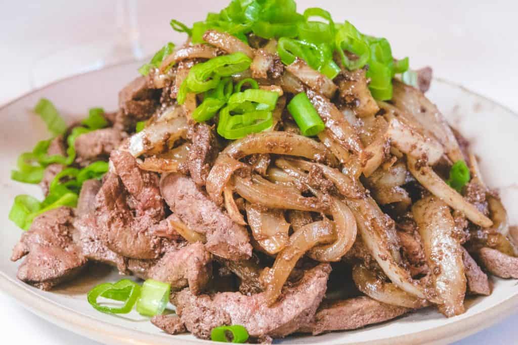 close up shot of liver and onions with green onion garnish
