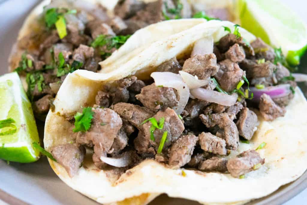 Lomo Saltado tacos with lime wedges