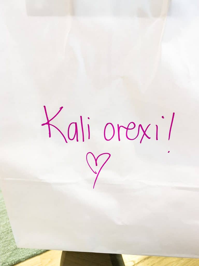 white paper bag with kali orexi! written in pink with a heart