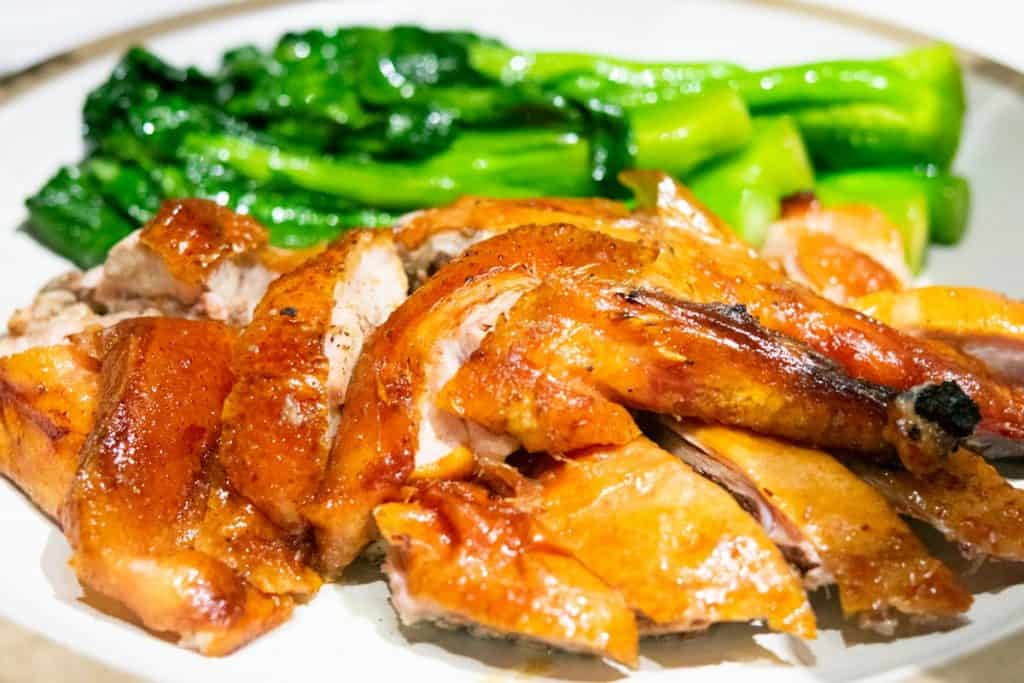 sliced roast duck with steamed greens on a plate
