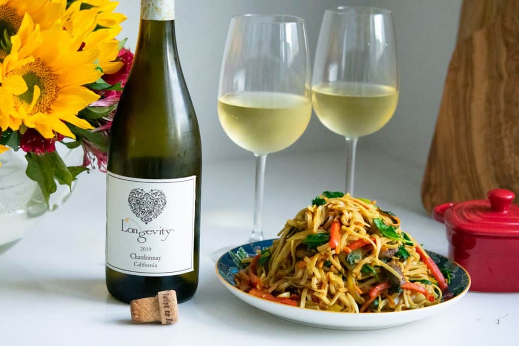 2 glasses of Longevity chardonnay with a plate of Singapore curry noodles