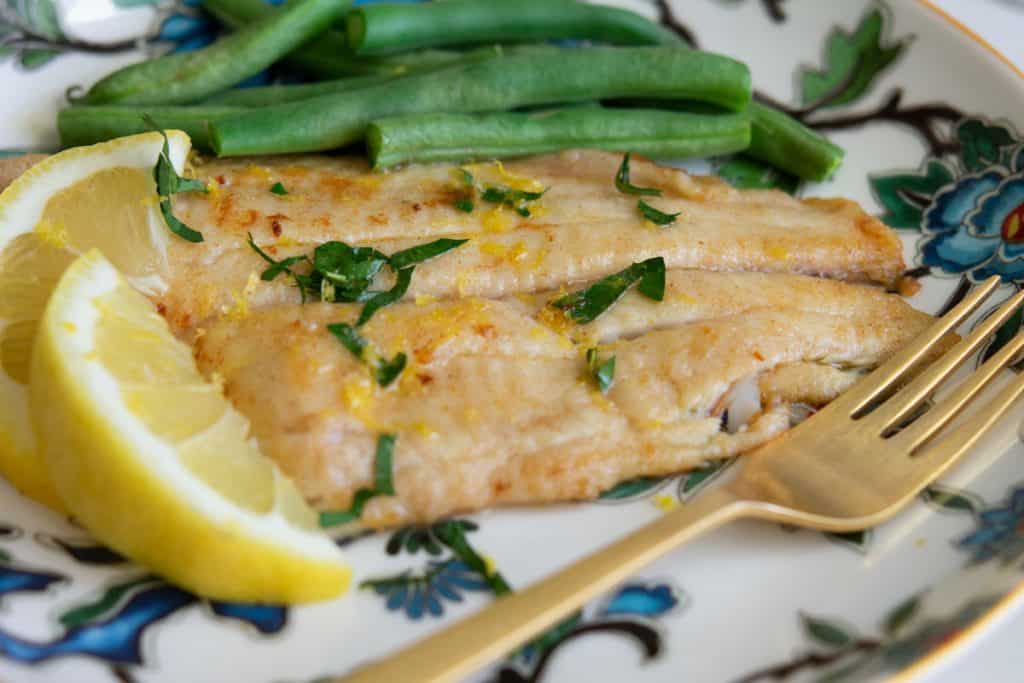 sole meuniere on a plate with green beans and lemon