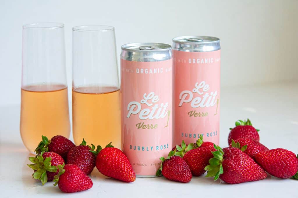 Le Petit Verre Bubbly Rose cans with flute glasses and fresh strawberries