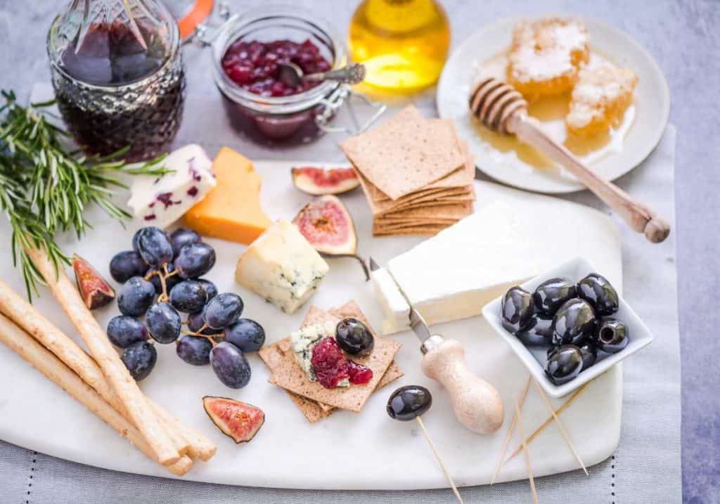 cheese board with grapes, breadsticks, and honey