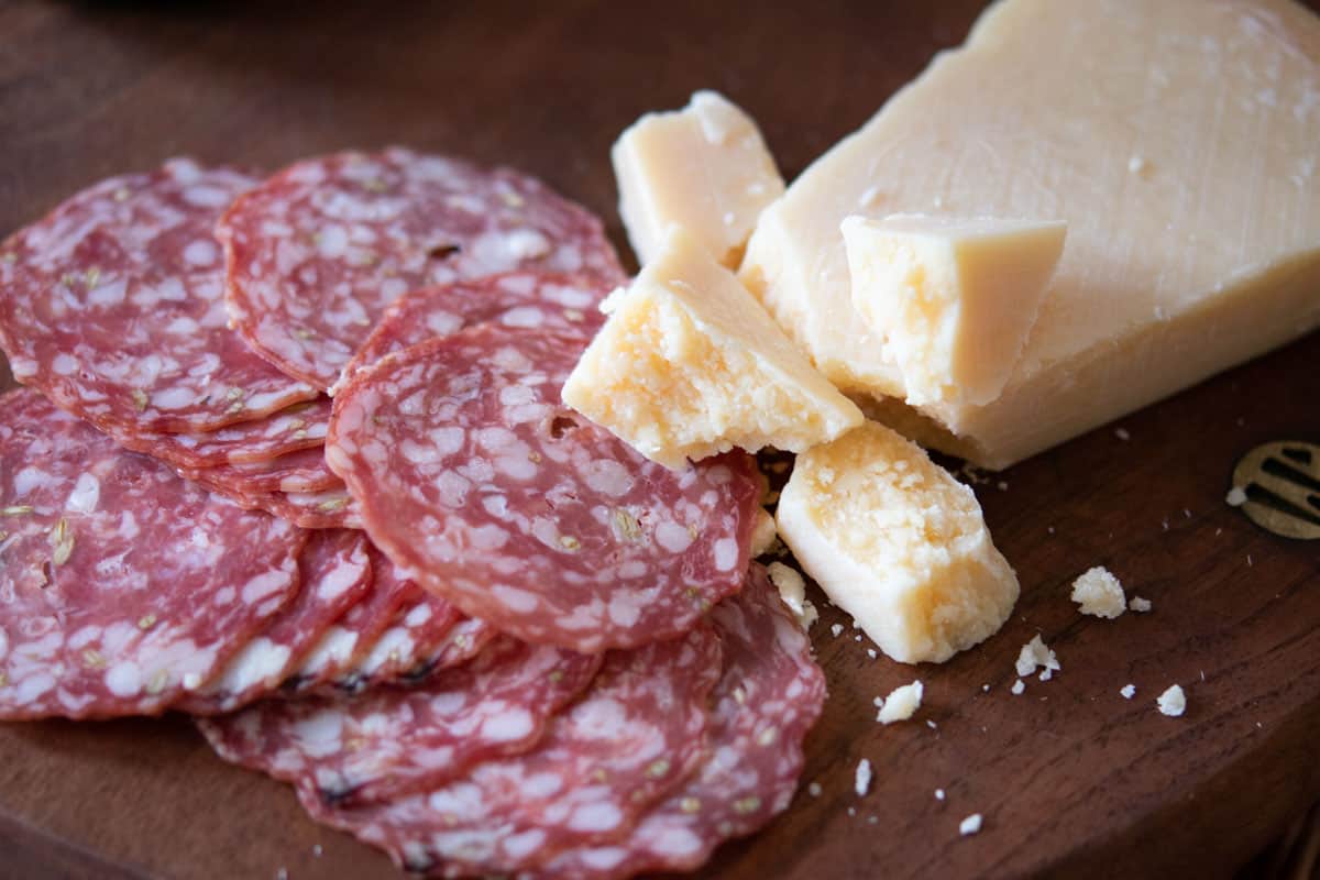 slices of salami and grano padano cheese on a wood cutting board