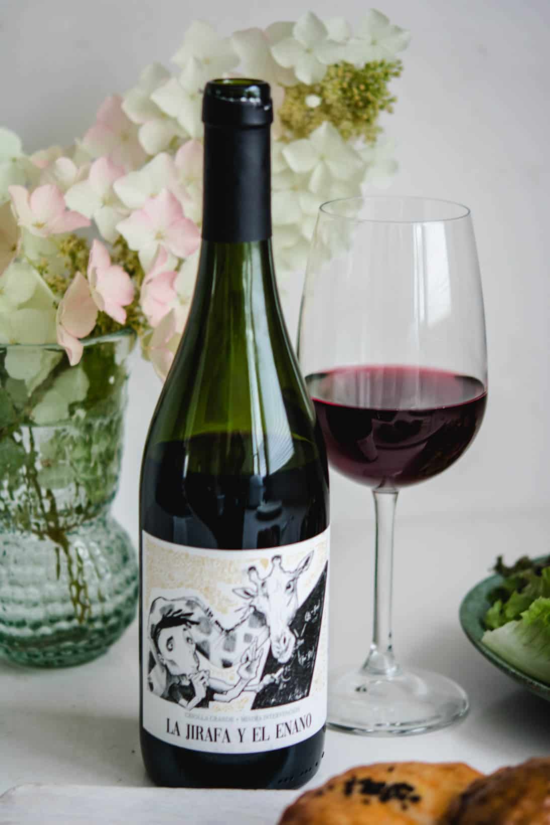 Close up shot of a bottle of Criolla Grande wine with a glass and white flowers in the background