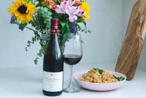Domaine Carneros Pinot Noir bottle and glass with a pink bowl of pad thai
