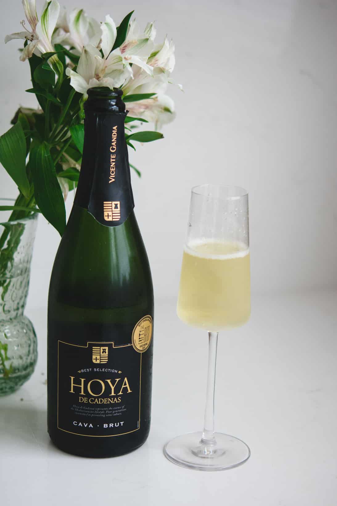 Hoya di Cardenas bottle and glass of cava wine with white flowers in the background