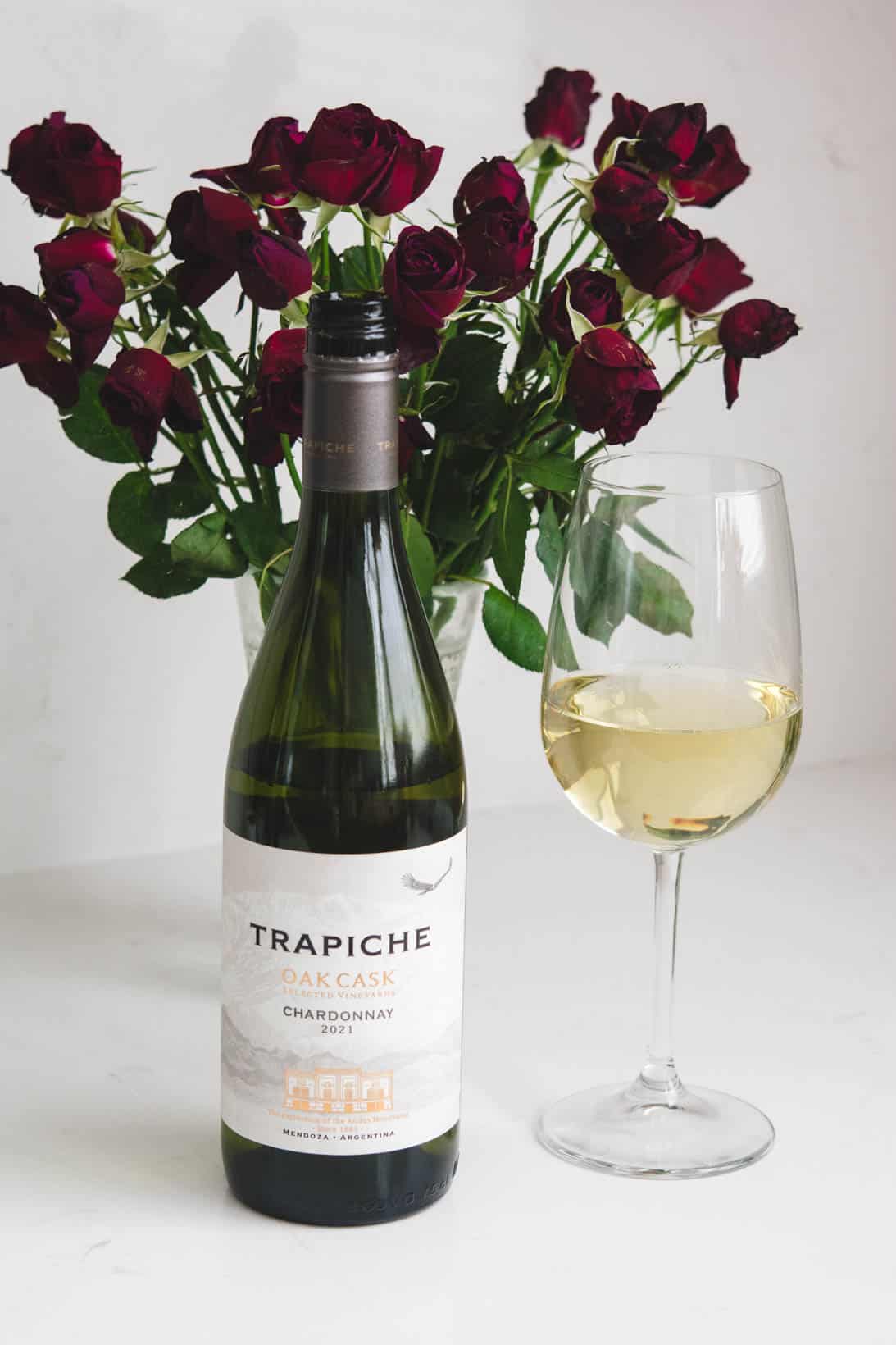 Wine bottle and glass of Trapiche Chardonnay with red roses in the background