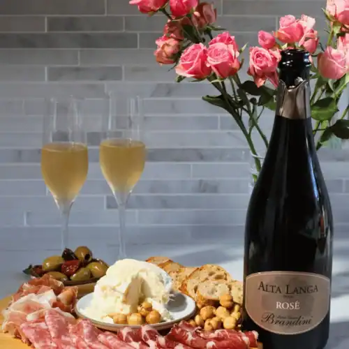 Alta Langa wine bottle and 2 glasses of wine with a cheese and charcuterie board