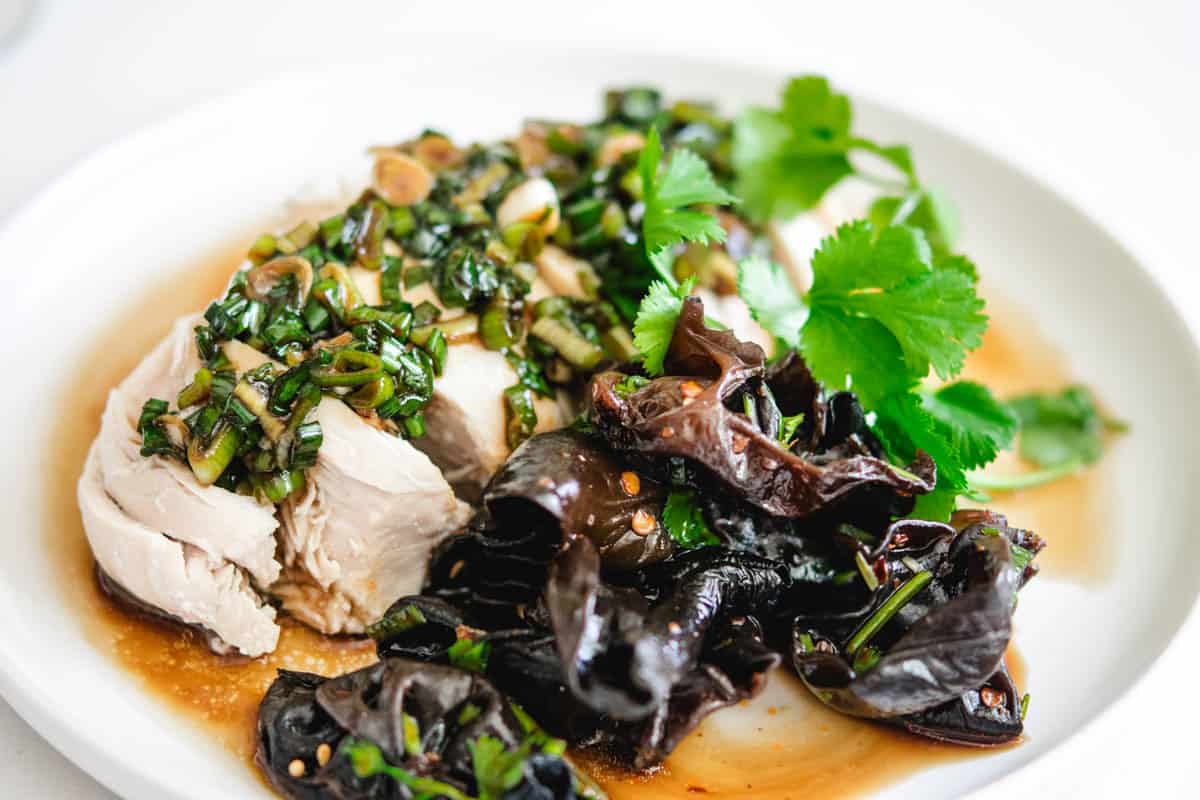 Delicious poached chicken topped with garlic, herbs, and fresh cilantro, served with sautéed black f.