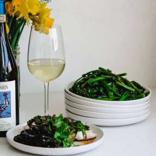 Fresh green beans served with white wine and gourmet dishes on a white table.