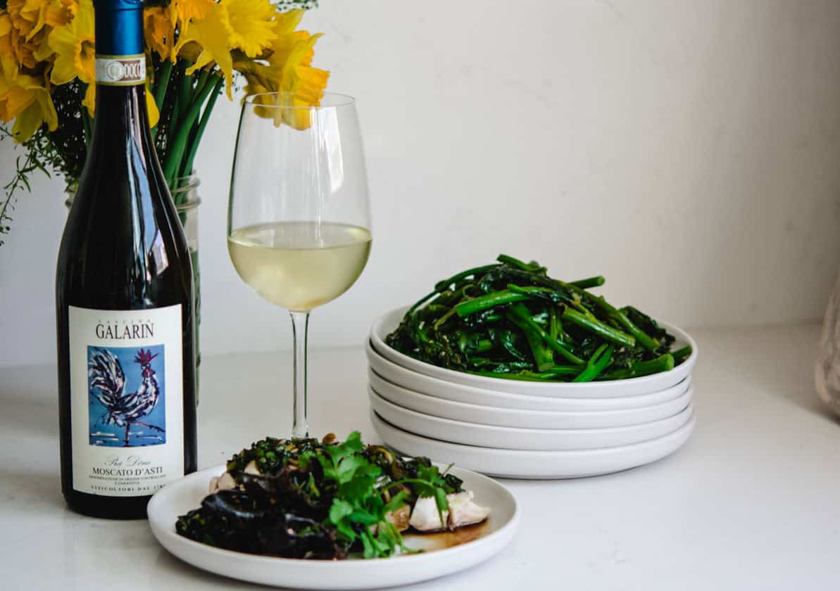 Fresh green beans served with white wine and gourmet dishes on a white table.
