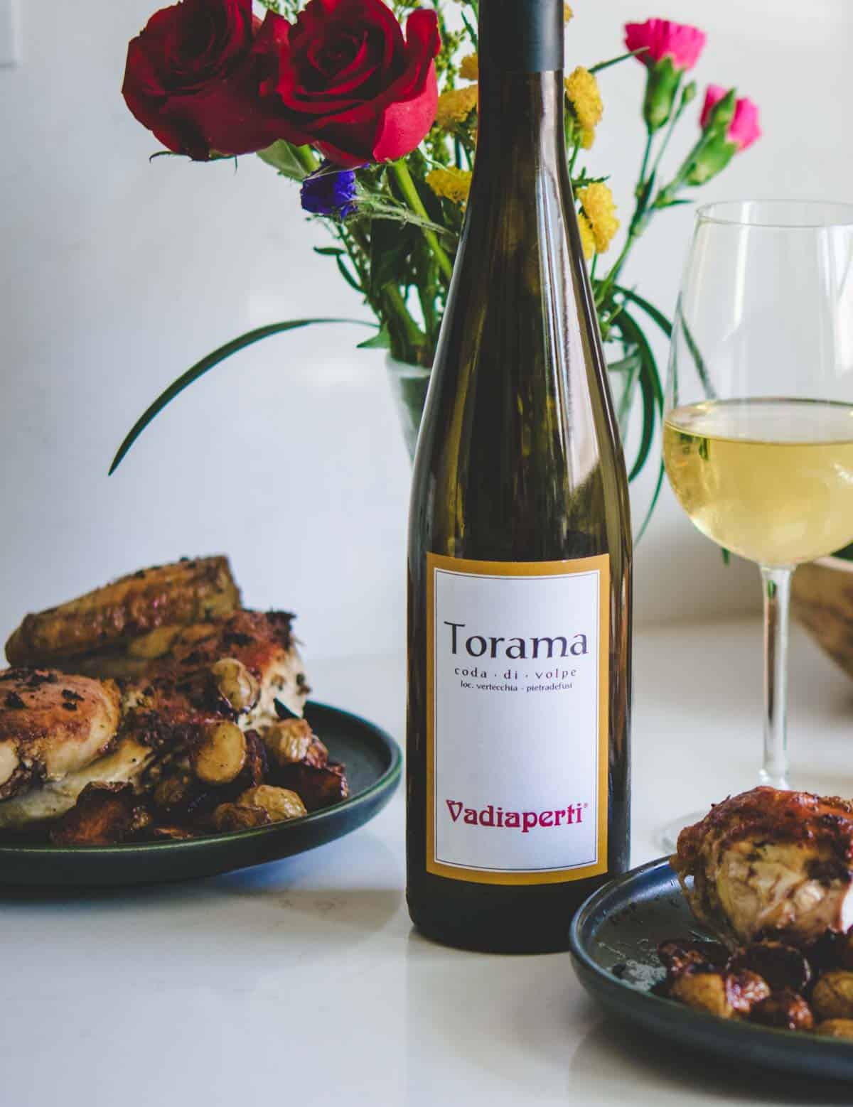 Torama Vadiaperti white wine bottle with flowers and food.
