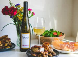 Gourmet meal with wine, flowers, and fresh salad on a white table.