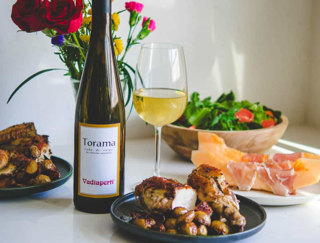 Coda di Volpe wine and gourmet food setup with salad and cheese.